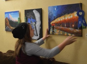 Alivia McClain, 11, adjusts her first place and Robert Pastorella Sr. Memorial Award winning painting on Monday at Groves Café and Coffee Bar. Mary Meaux/The News