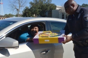 Sandra Louis, left, receives a king cake from Officer Antoine. Mary Meaux/The News 