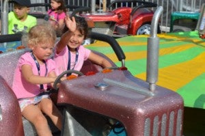 Bradlie Bell, 3, left, and Marlie Bell, 4, right, take a spin on the Tractors ride at the Nederland Heritage Festival on Friday. Mary Meaux/The News 