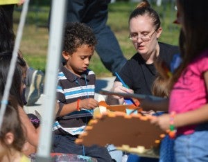 Marshall Ballard, left, and his mother Jessica Ballard paint a toy airplane glider during Art in the Park in Doorknobs Park in Nederland on Saturday. Mary Meaux/The News