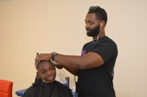 Ashford Garner, right, gives Derek Starks a haircut. Mary Meaux/The News