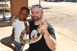 Ethan Brown, left, poses with Chester Moore of Kingdom Zoo and a Columbian red tail boa snake. Mary Meaux/The News