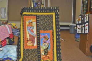 Quilt artist Laura Casmore holds up some of her work for the Kwanzaa celebration at the Port Arthur Public Library. Lorenzo Salinas/The News